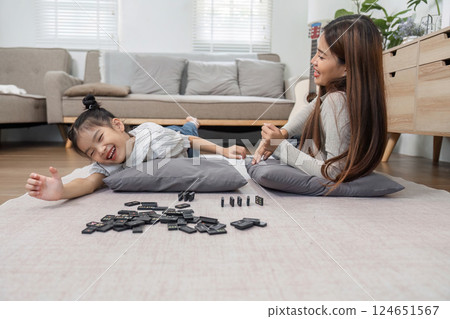 Family Joy and Game Night. A lively scene of a mother and daughter playing together on the floor, emphasizing the importance of quality time. 124651567