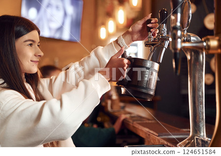Bartender pours beer. Woman is working in the bar Bartender pours beer. Woman is working in the bar 124651584