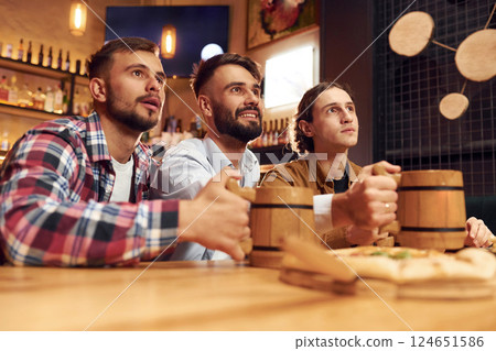 Watching TV. Three friends are in the bar drinking beer and having a good time Watching TV. Three friends are in the bar drinking beer and having a good time 124651586