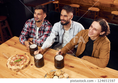 Top view. Sitting by the table. Three friends are in the bar drinking beer and having a good time 124651597