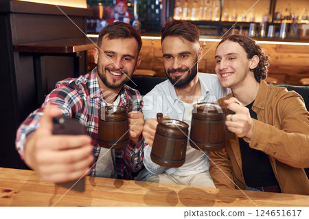 Making selfie. Three friends are in the bar drinking beer and having a good time 124651617