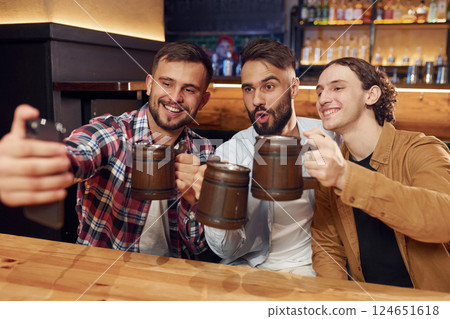 Making selfie. Three friends are in the bar drinking beer and having a good time 124651618