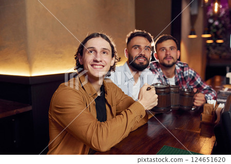 Sitting and smiling. Three friends are in the bar drinking beer and having a good time 124651620