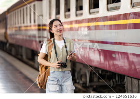 Travel and Adventure. A traveler exploring a train station with a camera and smartphone in hand. 124651636