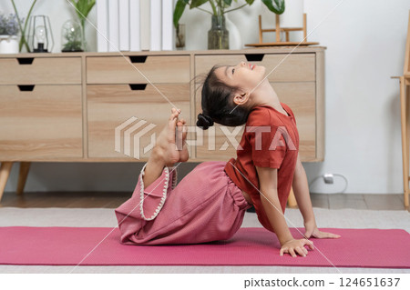 Yoga Practice and Flexibility. A child performs a yoga pose at home, showcasing flexibility and concentration. Yoga Practice and Flexibility. A child performs a yoga pose at home, showcasing flexibility and concentration. 124651637