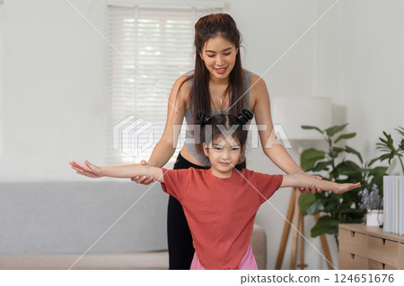 Balance and Growth. A mother helps her daughter foster balance and confidence through exercise. 124651676