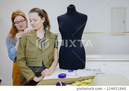 Atelier sewing workshop. female seamstress, fashion designer, takes measurements . Atelier sewing workshop. female seamstress, fashion designer, takes measurements . 124651848