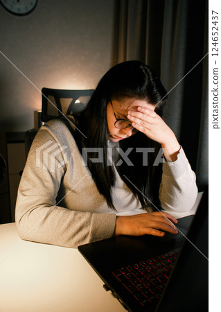 Tired woman working on computer touching her head because of headache. Office worker with migraine. Stressed overworked employee suffering from pain on workplace. Tired woman working on computer touching her head because of headache. Office worker with migraine. Stressed overworked employee suffering from pain on workplace. 124652437