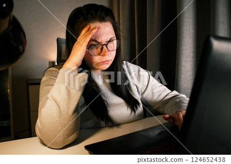 Hard working woman works on computer in her home office and tries to solve work problems. Feeling despair and burnt out from job issues. 124652438