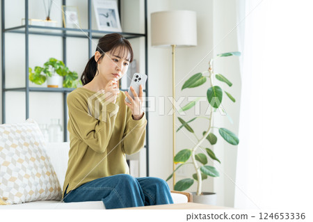 A young woman using a smartphone in the living room A young woman using a smartphone in the living room 124653336