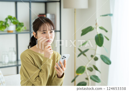 A young woman using a smartphone in the living room 124653338