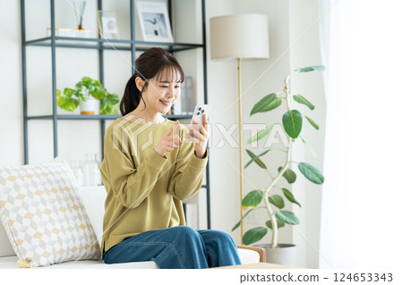 A young woman using a smartphone in the living room 124653343