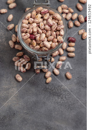 Glass jar full of dried pinto beans on gray top view, copy space. Traditional Latin American legumes 124653492