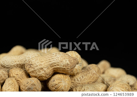 Pile of unpeeled peanuts in shell close-up on black background, place for text Pile of unpeeled peanuts in shell close-up on black background, place for text 124653989