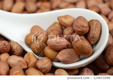 Raw peanut kernels in brown peel in a spoon close-up. Raw peanut kernels in brown peel in a spoon close-up. 124653996
