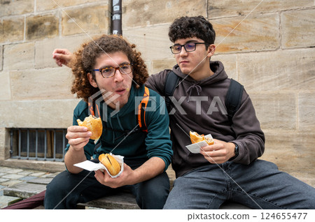 Nuremberg,Germany,August 1,2023. Two young Caucasians enjoy a break eating sandwiches with the typical Nuremberg sausage. As they eat they comment on the new flavours. Relaxation,friendship, lifestyle 124655477