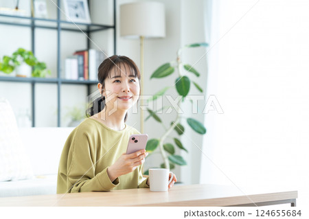 Young woman looking at her smartphone in the living room Young woman looking at her smartphone in the living room 124655684