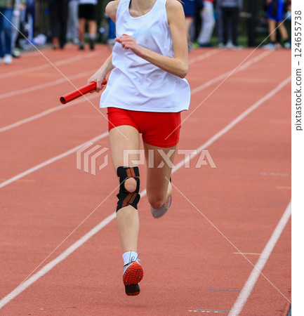 Relay Runner in Motion on Track During Athletic Competition Wearing a Knee Brace 124655738