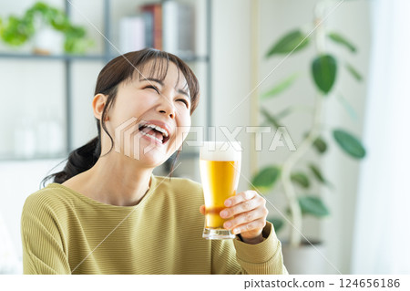 Young woman drinking beer in the living room 124656186