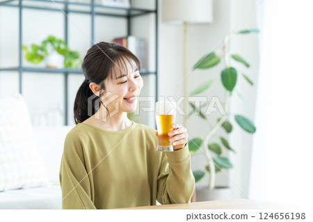 Young woman drinking beer in the living room Young woman drinking beer in the living room 124656198