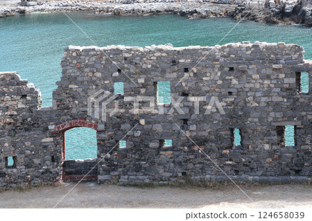 Stone wall with windows and turquoise sea. Italy and ruins of medieval castle. Tourism and attractions of Porto Venere. Stone wall with windows and turquoise sea. Italy and ruins of medieval castle. Tourism and attractions of Porto Venere. 124658039