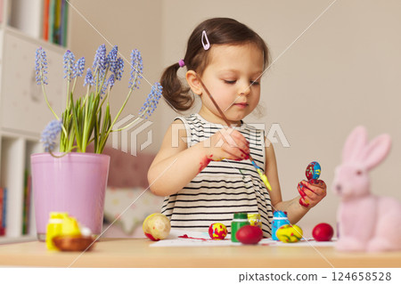 Little child girl paint Easter eggs at home. kid is preparing for Easter. Little child girl paint Easter eggs at home. kid is preparing for Easter. 124658528