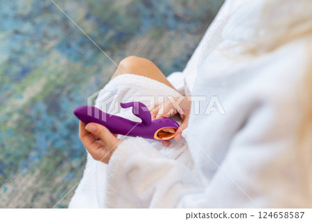 Woman in bedroom holding vibrator in hand 124658587