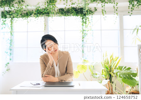 A middle-aged woman worried about her natural-looking office A middle-aged woman worried about her natural-looking office 124658752