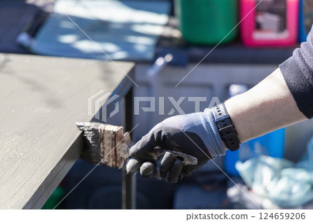 Male hand with paintbrush paints a garden table with green paint 124659206
