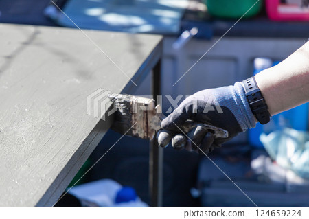 Male hand with paintbrush paints a garden table with green paint 124659224