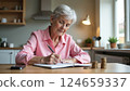 Senior Woman Writing Down Financial Records at Home: Budgeting for Retirement 124659337