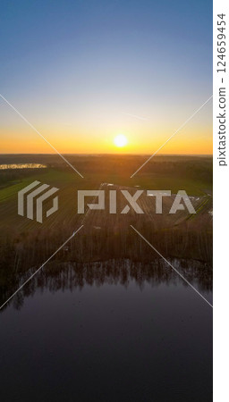 A Serene and Beautiful Sunset Over an Expansive Agricultural Landscape and Reflective Lake A Serene and Beautiful Sunset Over an Expansive Agricultural Landscape and Reflective Lake 124659454