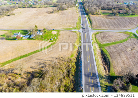 Rural intersection amidst vast farmland showcases nature tranquility in American countryside. 124659531