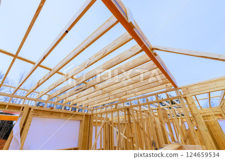 Builders are working on wooden frame structure beams roof timber beams in quiet suburban setting. 124659534