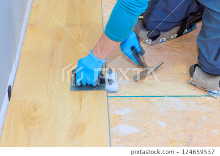Skilled worker expertly installs laminate flooring, highlighting his craftsmanship attention to detail. 124659537