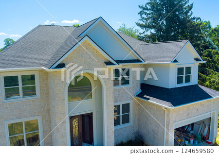 Beautiful house features grand entrance with large windows, surrounded by lush greenery Beautiful house features grand entrance with large windows, surrounded by lush greenery 124659580