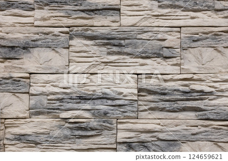 Textured stone wall featuring a natural, rustic design with warm tones and intricate patterns in a contemporary setting 124659621