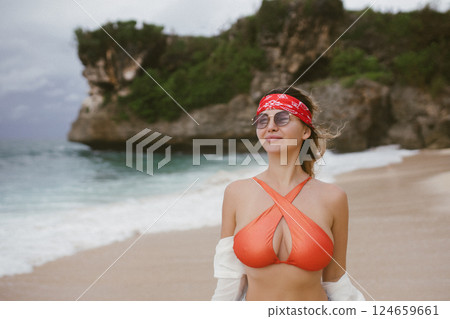 Seductive blond woman in sexy swimwear posing on the beach in sunset light. Summer tropical mood. Seductive blond woman in sexy swimwear posing on the beach in sunset light. Summer tropical mood. 124659661