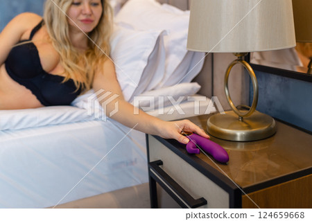 Young woman holding sex toy dildo vibrator in bed 124659668