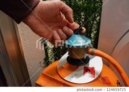 A man's hand opens a gas can. Concept of utilities, home heating, hazardous substances, home safety. 124659725