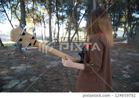 Young Girl Plays Bass Musical Instrument Under Trees In Nature 124659782