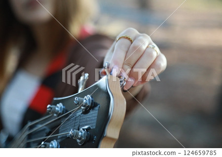 Girl Adjust Handles To Tune Bass Musical Instrument In The Park Girl Adjust Handles To Tune Bass Musical Instrument In The Park 124659785