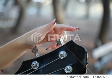 Girl Adjust Handles To Tune Bass Musical Instrument In The Park 124659789