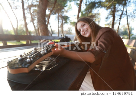 Girl Plays Bass Musical Instrument Sitting In Table In The Mountain Forest Girl Plays Bass Musical Instrument Sitting In Table In The Mountain Forest 124659791