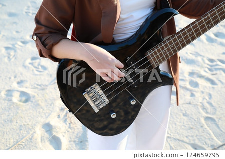 Girl Plays Bass Music Instrument On The Beach At Sunset Near Ocean 124659795