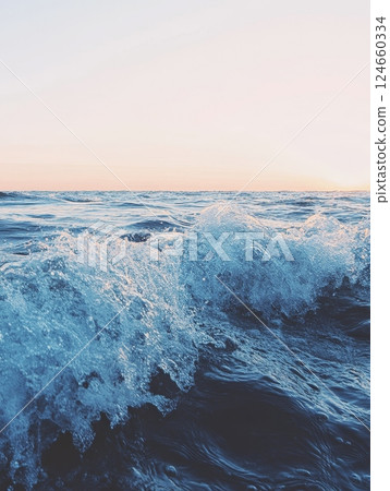 Powerful ocean waves crash and spray against a backdrop of a pastel sunset sky, showcasing the raw beauty and energy of the sea 124660334