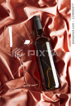 Bottle of red wine on pink satin background. Top view 124660477