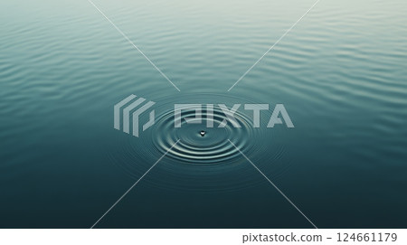 Single drop of water creating expanding circular ripples on a calm lake surface with soft, diffused light, creating a tranquil and meditative atmosphere 124661179
