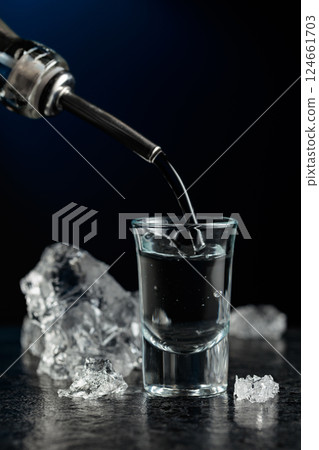 Crystal clear vodka or gin being poured into a glass. 124661703