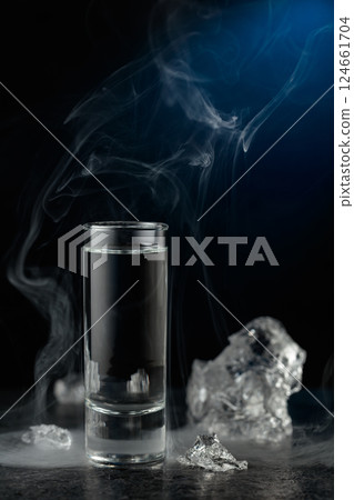 Crystal clear vodka or gin in a glass on a black stone table. Crystal clear vodka or gin in a glass on a black stone table. 124661704
